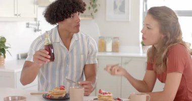 Kahvaltıdan zevk alan genç bir çift, mutfak masasında kreplerin üzerine şurup döküyorlar. Yemek, sabah, yemek, kaynaşma