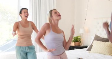 Çeşitli bayan arkadaşlar birlikte gülüyor ve dans ediyorlar. Parlak oturma odasında, arkadaşlığın tadını çıkarıyorlar. Kutlama, mutluluk, birliktelik, bağlanma, dans, sosyalleşme