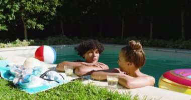 Havuzda dinlenen, çeşitli çiftler güneşli bir günde içki içip sohbet ediyorlar. Tatil, tatil, rahatlama, açık hava, içecek, güneş ışığı.