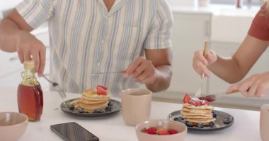 Kahvaltıda krep ve çilek yiyorlar. Çeşitli çiftler gülümsüyor ve evde sohbet ediyorlar. Sabah, sağlıklı, yaşam tarzı, rahatlama, yemek, mutluluk