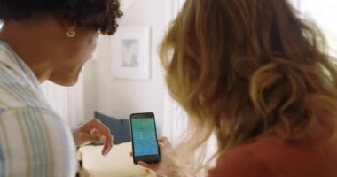 Çeşitli çiftler oturma odasındaki akıllı ev aletlerini kontrol etmek için akıllı telefon kullanıyor. Teknoloji, yenilik, uzaktan kontrol, bağlantı, otomasyon, kolaylık