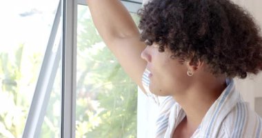 Genç adam pencereden dışarı bakıyor, güneşli bir günün keyfini çıkarıyor, evde rahat bir ifadeyle. Rahatlama, güneş ışığı, tefekkür, rahatlık, sükunet, mutluluk