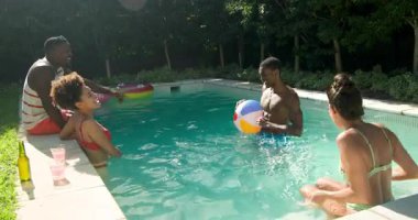 Çeşitli arkadaşlar havuz partisinden, su sıçratmaktan ve dışarıda plaj topuyla oynamaktan hoşlanıyorlar. Yaz, eğlence, güneş, tatil, eğlence