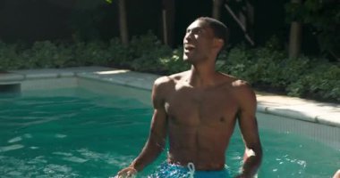 Havuzda ferahlatıcı yüzmeyi seven, gülümseyen ve neşeyle su sıçratan bir adam. Yüzme, su, eğlence, eğlence, tatil, eğlence.