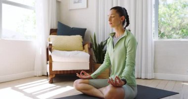 Evde yoga minderi üzerinde meditasyon yapan bir kadın. Huzurlu bir rahatlamayı kucaklıyor. Meditasyon, farkındalık, sükunet, sağIık, kendine dikkat, denge.