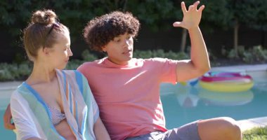 Havuz başında dinlenen, sohbetin ve açık havada güneşli bir günün tadını çıkaran genç bir çift. Tatil, rahatlama, rahatlama, güneş ışığı, yüzme, seyahat