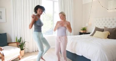 Çeşitli bayan arkadaşlar rahat yatak odasında neşeyle dans ediyor, evde eğleniyor ve rahatlıyor. Arkadaşlık, kutlama, yaşam tarzı, mutluluk, rahatlama, kahkaha