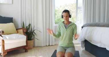 Yeşil giysili bir kadın evde yoga minderinin üzerinde akıllı telefon kullanıyor. Odaklanıyor. Spor, sağlık, egzersiz, teknoloji, egzersiz, meditasyon