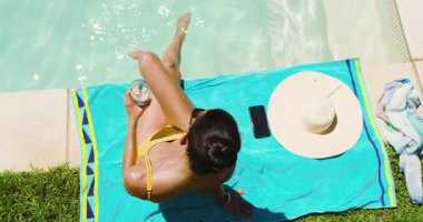 Havuzda dinlenen, sarı mayolu kadın güneşli bir günde içkinin tadını çıkarıyor. Tatil, tatil, yaz, güneş banyosu, dinlenme, mayo