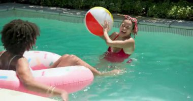 Gülen farklı bayan arkadaşlar bilardo gününün tadını çıkarıyorlar, plaj topuyla oynuyorlar ve yüzer vaziyette dinleniyorlar. Boş zaman, yaz, tatil, eğlence, eğlence, açık hava.