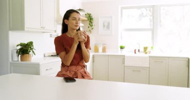 Mutfakta akıllı telefon kullanan, kahvenin tadını çıkaran ve evde dinlenen bir kadın. Yaşam tarzı, eğlence, teknoloji, rahatlama, sabah, gündelik