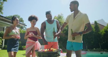 Çeşitli arkadaşlar havuz başında barbekü yapıyor, güneşli bir günde ızgara yapıyor ve içiyor. Açık hava, parti, toplanma, yaz zamanı, boş zaman, gündelik