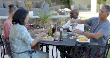 Bahçe yemeğinin tadını çıkaran çeşitli son sınıf arkadaşları bahçe masasında neşeli bir tostun içinde kadehleri kaldırıyorlar. Kutlama, arkadaşlık, bahçede yemek, toplanma, mutluluk, şerefe