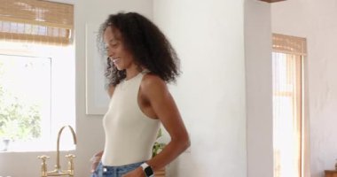 Mutfakta gülümseyen bir kadın, güneşli bir günün tadını çıkarıyor. Yurt içi, yaşam tarzı, mutluluk, eğlence, neşe, sabah