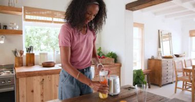 Mutfakta smoothie karıştıran, gülümseyen ve evde yemek pişirmekten zevk alan bir kadın. Mutfak, sağlıklı yaşam tarzı, ev, ev, mutluluk.