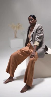 Dikey video: Modern moda stüdyo ortamında kendine güvenen şık kıyafetli bir model. style, photoshoot, confidence, modelleme, moda, giyim