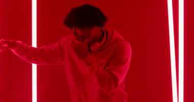 Sis yükseldikçe kulaklık takan neon tüplerin arasında dans provası yapan Afrikalı Amerikalı bir adam. Neon, atmosfer, koreografi, şehir, canlı, sinematik, hareket