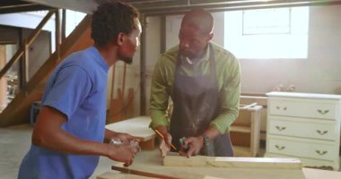 Tahta yerleştirdikten sonra, Afrika kökenli Amerikalı akıl hocası ve çırak tezgahın üzerine odun ölçüp işaretlediler. Sanatçılık, ahşap işçiliği, el emeği, alet kullanımı, atölye çalışması, adanmışlık, beceri geliştirme