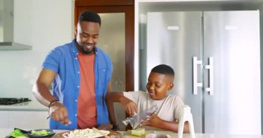 Afro-Amerikan baba-oğul tezgahına yaklaşıyoruz. Akşam yemeği için peyniri pizza hamurunun üzerine rendeliyorlar. Aile, yemek pişirme, işbirliği, mutfak, aşçılık, kaynaşma, ev