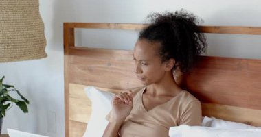 Yatakta dizüstü bilgisayar kullanan, uzaktan çalışan gülümseyen bir kadın. Uzaktan çalışma, teknoloji, ev ofisi, konfor, yaşam tarzı, seyahat