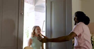African American man unlocking front door, hugging friends holding straw hat, guiding toward tour. Welcoming, friendship, hospitality, interior, modern, lifestyle, social