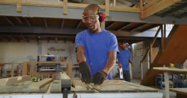 Afro-Amerikan erkek takımı kalasları masa testeresi ile kesiyor ve teftiş tahtalarını inceliyor. Sanatçılık, atölye, işbirliği, güvenlik, profesyonellik, sanayi, inşaat
