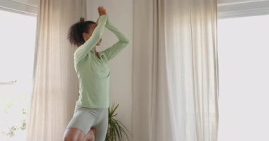 Evde yoga yapan bir kadın, pencerenin yanında zarif bir şekilde dans ediyor. Sağlık, fitness, meditasyon, huzurlu, sağlıklı yaşam tarzı, esneklik