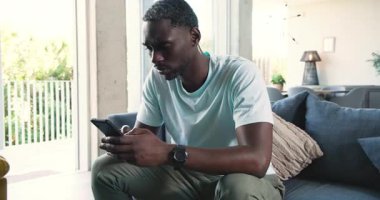 Oturma odasındaki koyu mavi koltukta oturan Afro-Amerikalı adam yeşil bitkilerle kafa yoruyor. Düşünce, sükunet, modern, minimalist, yaşam tarzı, yeşillik, rahatlama