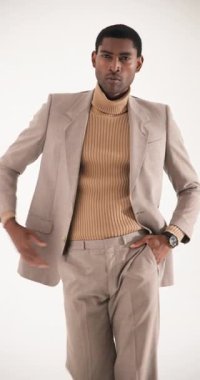 Dikey video: Bej takım elbiseli şık adam ceketini ayarlıyor, modern moda trendlerini sergiliyor. tarz, erkek giyim, zarafet, güven, sofistike, moda