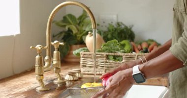 Evde, mutfaktaki taze kırmızı ve sarı dolma biberleri akan suyla yıkamak. Sebzeler, yemek pişirme, sağlıklı, renkli, beslenme, malzemeler