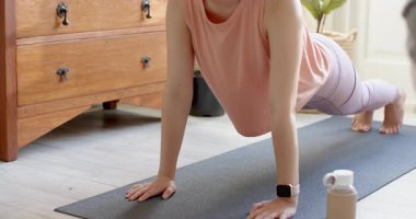 Settling into plank on black mat, Asian female doing knee tuck and forearm plank at home. Fitness, workout, balance, strength, yoga, wellness, home fitness