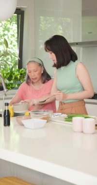 Dikey video: Anne ve kızı birlikte yemek hazırlıyor, kaliteli zaman geçiriyorlar. Aile, yemek pişirme, kaynaşma, yaşam tarzı, ev, ev
