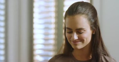 Yirmili yaşlardaki bir kadın jaluzi ile toz fırçası karıştırıyor, pürüzsüz bir son için yanakları süpürüyor. Güzellik, kadınlık, bencillik, cilt bakımı, zarafet, incelik, doğal ışık.