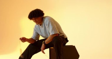 Çerçeveye giriyor, yirmili yaşlarda bir erkek stüdyo amfisine yerleşiyor, mikrofon çeviriyor ve vokal çalışıyor. Performans, müzisyen, sahne, eğlence, sanatçılık, ifade, vokalizasyon