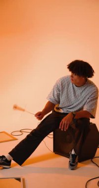 Dikey video: Genç adam mikrofonu tutuyor, müzik stüdyosunda rahat. Müzisyen, kayıt, gündelik