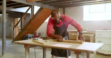 Kereste klempe dayanır, siyah erkek iş arkadaşları atölyede odun zımparalar ve bitirmeyi tartışırlar. Zanaatkar, atölye, marangozluk, inşaat, işçilik, sanayi