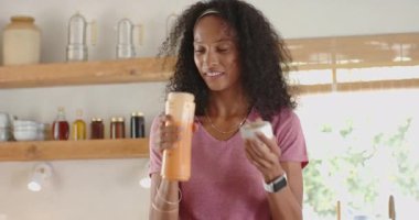 Mutfakta gülümseyen kadın bardağa taze meyve suyu dolduruyor, evde sabah rutininin tadını çıkarıyor. Yaşam tarzı, kahvaltı, mutluluk, sağlıklı, içecek, beslenme