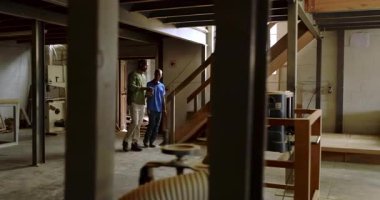 Tablet kullanarak ve çerçeve parçalarını inceleyerek atölyedeki Afrikalı Amerikalı iş arkadaşları aşağı iniyor. Sanatçılık, takım çalışması, imalat, sanayi, teknik, işbirliği, çalışma alanı