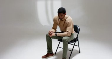 Afrika kökenli Amerikalı bir adam zamanı fark ediyor. Stüdyoda pencere camlı gölgeli bir sandalyede kol saatini kontrol ediyor. Profesyonel, düşünceli, minimalist, içten, düşünceli, zarif, modern.