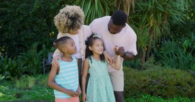 Afro-Amerikan ailesi, çocukları kucaklayan ve rehberlik eden ebeveynler olarak kürsüden portre için poz veriyor. Aile, ebeveynlik, birliktelik, açık hava, mutluluk, yaşam tarzı, portre