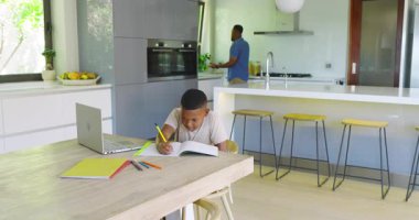 Afro-Amerikalı baba akıllı telefon çeviriyor, okul çocuğu laptopta ödev yapıyor, fotokopi çekiyor. Aile, eğitim, teknoloji, konsantrasyon, yerli, çalışma alanı, çoklu görev