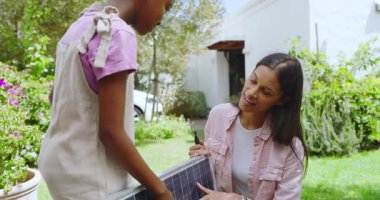 Anne ve çocuk güneşli bahçede güneş paneli teknolojisini keşfediyorlar. Sürdürülebilirlik, yenilenebilirlik, bağlanma, yenilik, öğretim, çevre