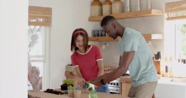 Çeşitli çiftler mutfaklarında tohum ekiyor, gülümsüyorlar, evde. Bahçe işleri, takım çalışması, kapalı tesisler, sürdürülebilirlik, arkadaşlık, işbirliği