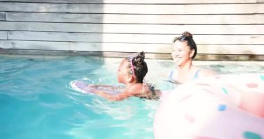 Kız eve mor bir kickboard ile giriyor, annesi tekmeleri destekliyor ve yüzme güvenini arttırıyor. Aile, su, rahatlama, eğitici, canlı, boş zaman, açık hava