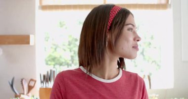 Kırmızı tişörtlü, evinde tatilin tadını çıkaran, rahatlamış ve mutlu hisseden, gülümseyen bir kadın. Boş zaman, rahatlama, mutluluk, sükunet, yaşam tarzı, gündelik