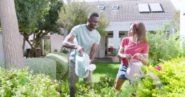 Çeşitli çiftler bahçeyle uğraşmaktan zevk alıyorlar, bahçedeki bahçelerde gülücükler saçan bitkileri suluyorlar. Açık hava, takım çalışması, bahçıvanlık, doğa, yaşam tarzı.