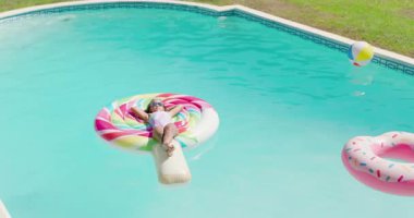 Havuz akıntısı, kamera döndükçe şişme bebekler arasında uzanan lolipop salını sürüklüyor. Yaz zamanı, boş zaman, rahatlama, su, canlı, oyuncu, açık hava