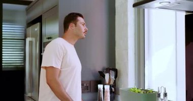 Buzdolabına bakmak, sonra mutfak penceresinden bakmak, kameraya dönen ve kahkahaları paylaşan bir adam. Modern, gündelik, hayat tarzı, samimi, neşeli, içten, parlak.