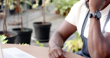 Bahçedeki bitkilerle ilgilenen, seradaki işine odaklanmış önlüklü Afrikalı Amerikalı bir adam. Bahçıvanlık, bahçıvanlık, açık hava, tarım, işçilik, yeşillik