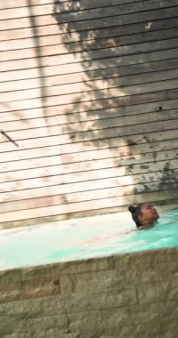 Dikey video: Açık havuzda birlikte yüzmek, anne ve çocuk neşeli anları paylaşıyor. Aile, kaynaşma, yaz, eğlence, eğlence, su sporları